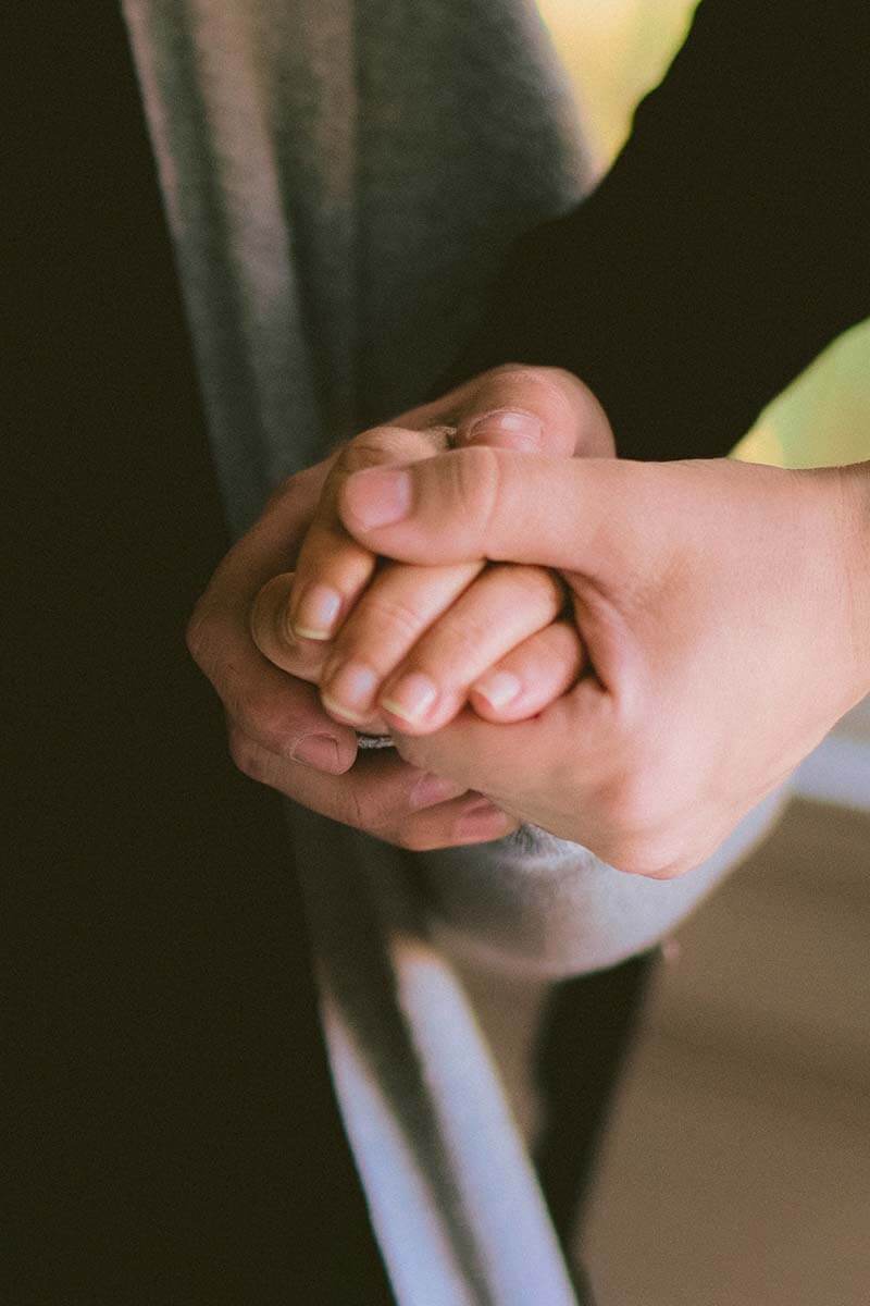 Une main d'adulte qui tient une main d'enfant pour l'accompagner en séance de kinésiologie