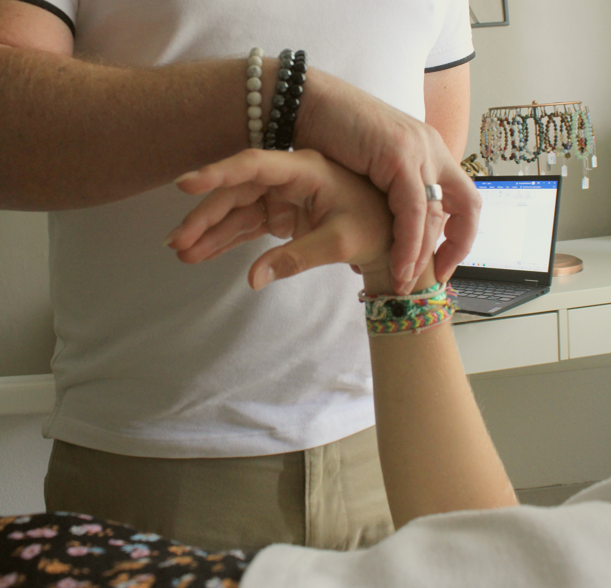 main du kinésiologue posée sur la main du client allongé sur une table de massage en séance de kinésiologie appliquée